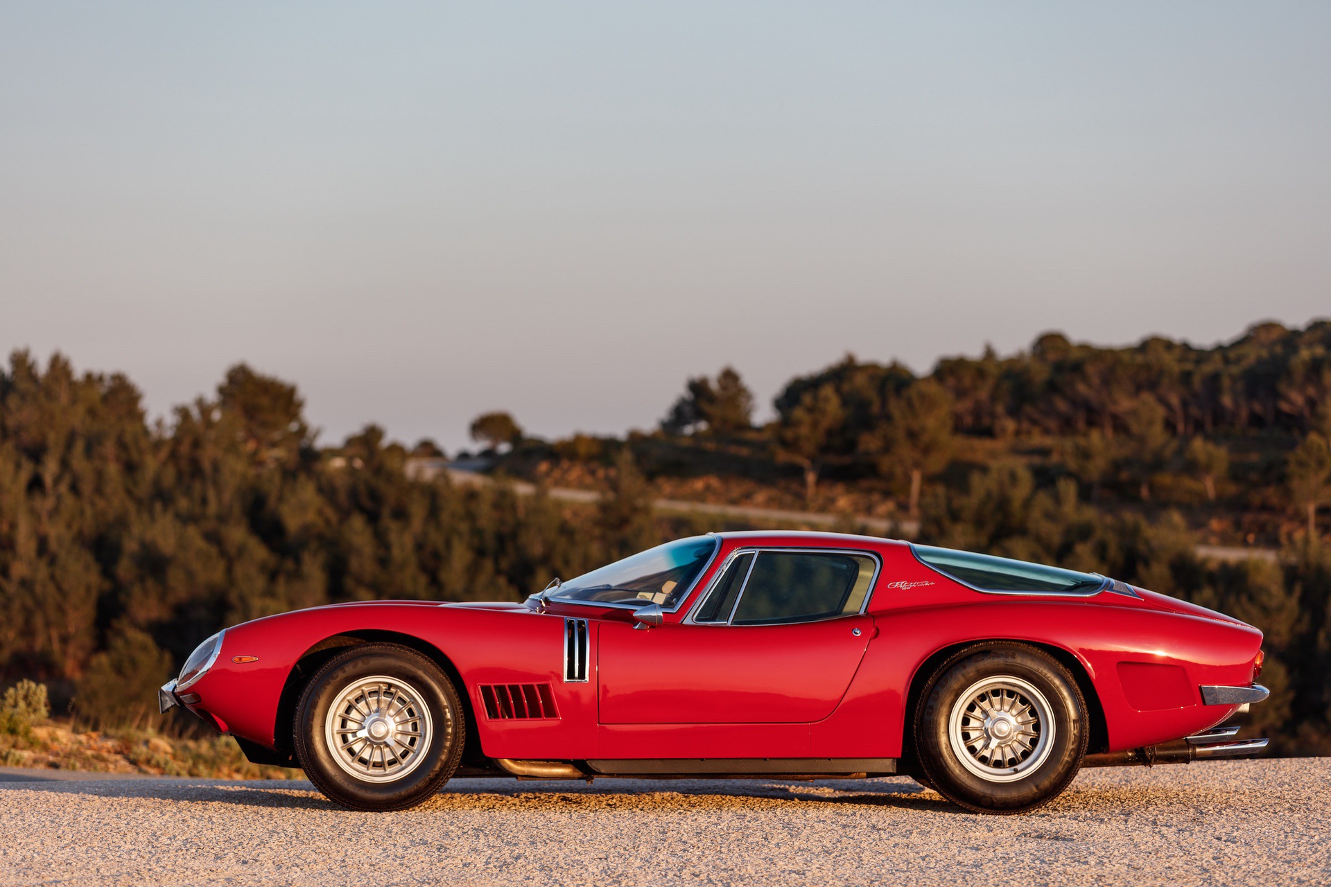 Red Bizzarrini 5300 GT on road at sunset