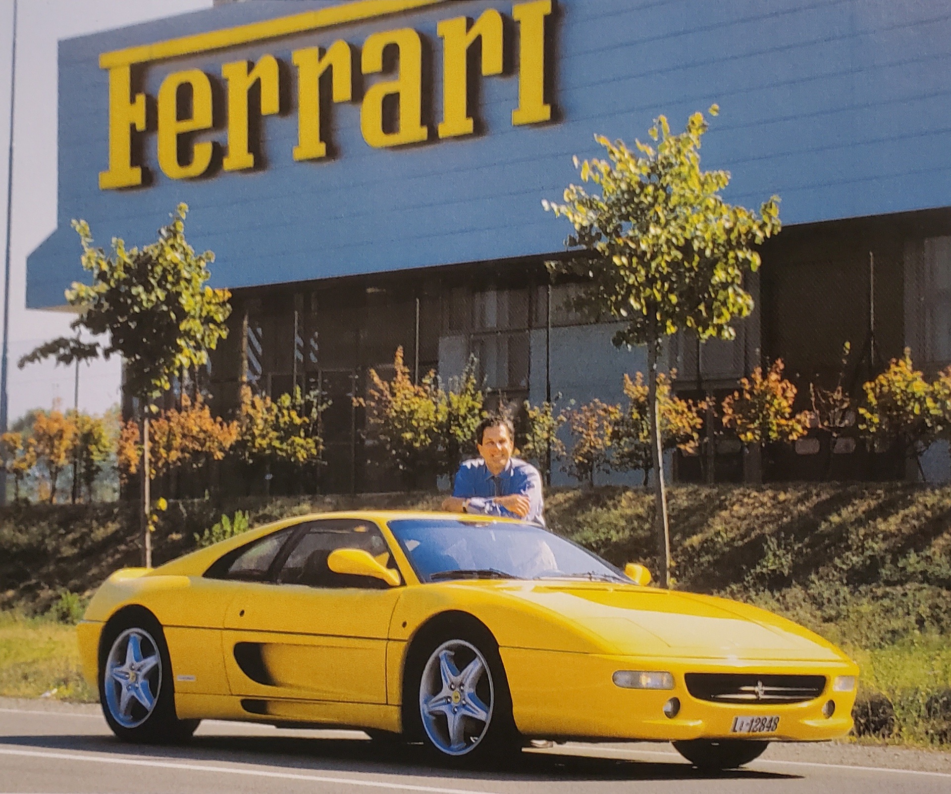 Luigi Chinetti Jr. with yellow Ferrari outside Ferrari factory in the late 1980s