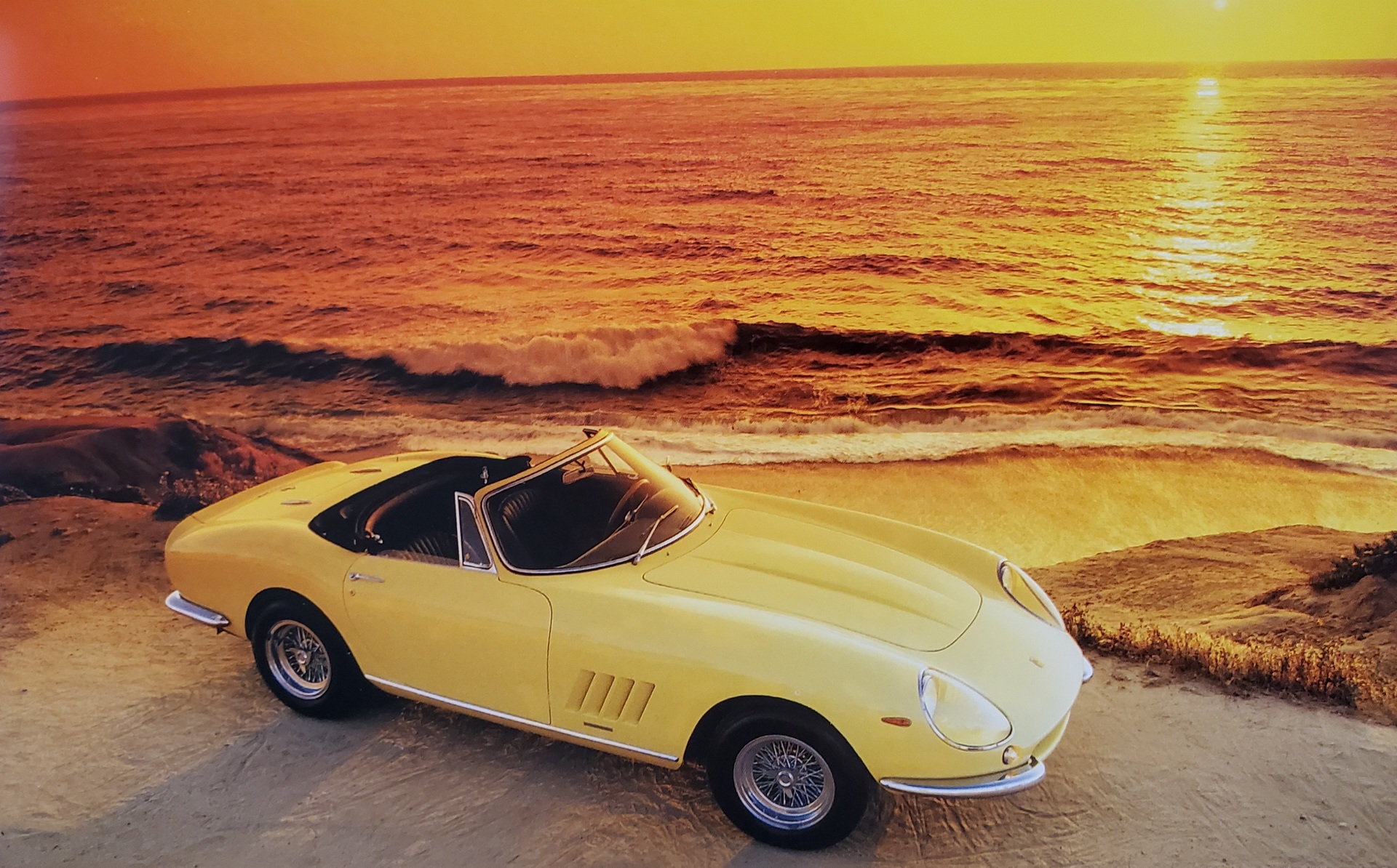 Yellow Ferrari 275 GTS/4 NART Spyder in front of ocean at sunset